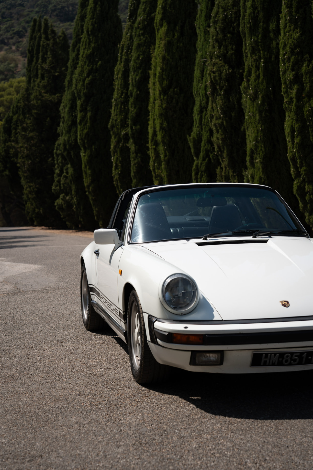 White classic Porsche 911 Targa on a cypress-lined road of the French Riviera